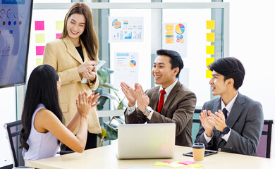 Asian young pretty professional successful businesswoman staff standing greeting say thank you when finishing presentation while male and female colleagues clapping hands together admire compliment
