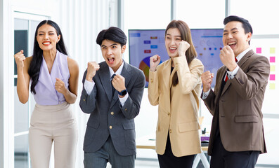 Group of young happy male and female professional successful businessman and businesswoman colleagues partnership in formal business suit standing rise fists up smiling celebrating job done together