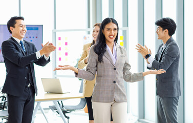 Millennial Asian young happy beautiful female businesswoman employee staff in formal business suit standing smiling crossed arms while male colleagues throwing papers celebrating job achievement done