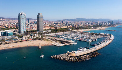 Fototapeta na wymiar Scenic aerial view of famous Olympic Harbor Marina with docked white pleasure yachts on background of modern cityscape of Barcelona on Mediterranean coast on summer day, Spain..