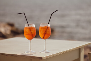 Two Aperol Spritz cocktails on the table in front of the sea background