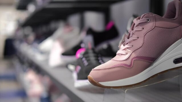 Shelf with sneakers in the store. The shoe store provides a large selection of shoes for sports and everyday use. Shoes of different models, sizes and colors. Buying shoes in the supermarket.