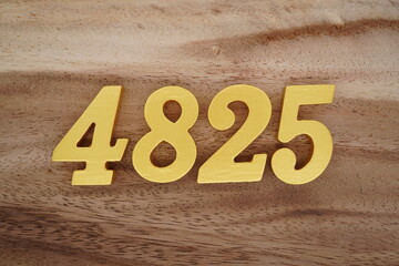 Golden Arabic numerals on a real brown and white wooden floor number 4825