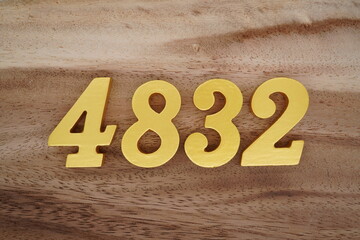 Golden Arabic numerals on a real brown and white wooden floor number 4832