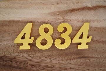 Golden Arabic numerals on a real brown and white wooden floor number 4834