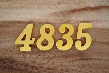 Golden Arabic numerals on a real brown and white wooden floor number 4835