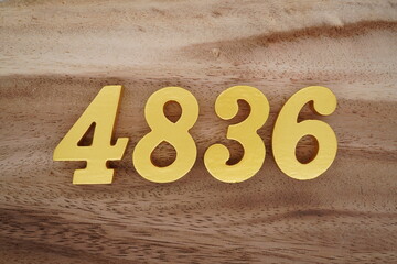 Golden Arabic numerals on a real brown and white wooden floor number 4836