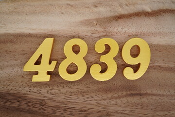 Golden Arabic numerals on a real brown and white wooden floor number 4839