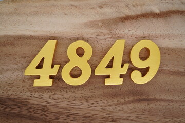 Golden Arabic numerals on a real brown and white wooden floor number 4849