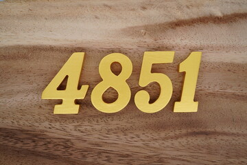 Golden Arabic numerals on a real brown and white wooden floor number 4851