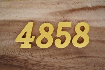 Golden Arabic numerals on a real brown and white wooden floor number 4858