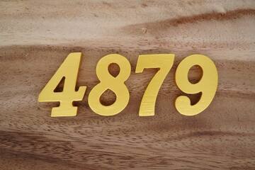 Golden Arabic numerals on a real brown and white wooden floor number 4879