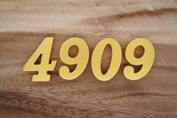 Golden Arabic numerals on a real brown and white wooden floor number 4909