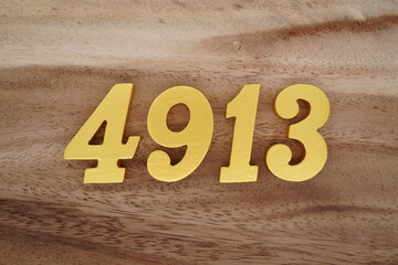 Golden Arabic numerals on a real brown and white wooden floor number 4913