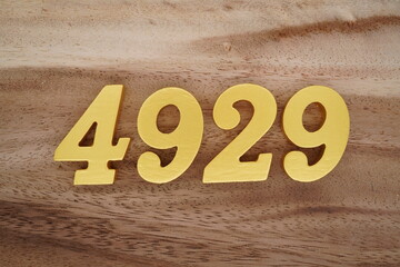 Golden Arabic numerals on a real brown and white wooden floor number 4929