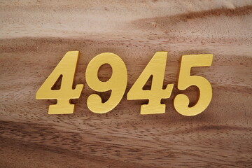 Golden Arabic numerals on a real brown and white wooden floor number 4945