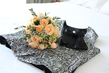 Orange roses and silver vests are prepared on the bed