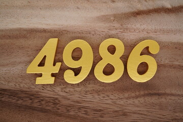 Golden Arabic numerals on a real brown and white wooden floor number 4986