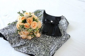 Orange roses and silver vests are prepared on the bed