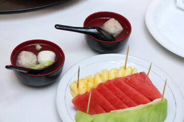 two bowls of meatballs, pineapple and watermelon