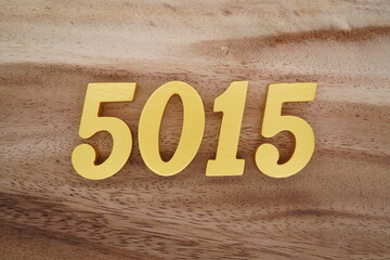 Golden Arabic numerals on a real brown and white wooden floor number 5015