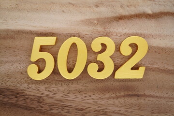 Golden Arabic numerals on a real brown and white wooden floor number 5032