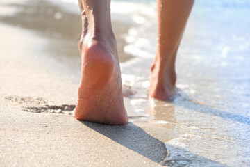 woman walking to sea and beach on a beautiful island Ocean foam wrapped around a girl's leg. Her legs touched the splashing water. Hit the skin on the legs and she walked in the soft sunshine morning
