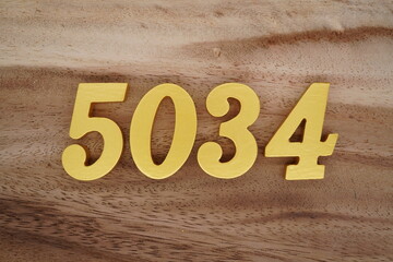 Golden Arabic numerals on a real brown and white wooden floor number 5034