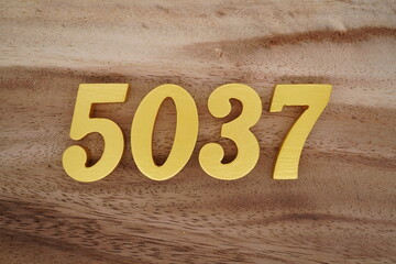 Golden Arabic numerals on a real brown and white wooden floor number 5037