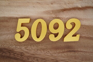 Golden Arabic numerals on a real brown and white wooden floor number 5092