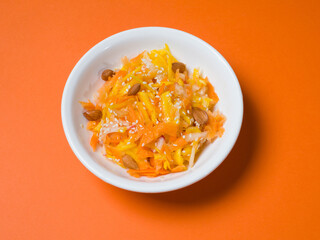Pumpkin salad in a white plate on an orange background. Studio photography. View from above