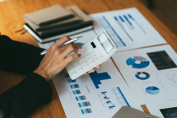 Young businessman using calculator and laptop computer is now finalizing sales this year to analyze sales growth by the world at work.