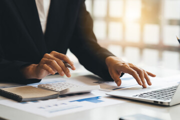 A businesswoman or female financial worker analysing financial data report, pointing pen on paperwork.