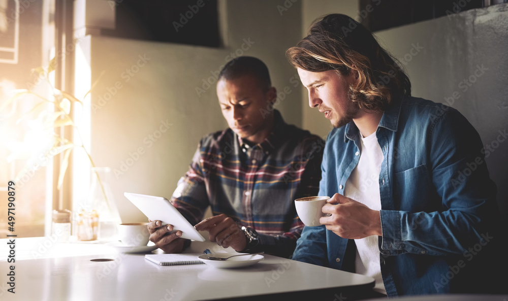 Poster that doesnt look good. shot of two friends using a tablet while having coffee in a coffee shop.