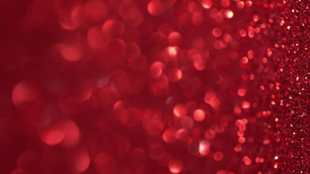Red Glitter Background. Magic dust, shiny texture, holiday lights, flying particles form a beautiful bokeh. Shining festive Christmas backdrop. Vertical Video