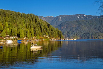 Coastal village and Marina at the Deep Bay in North Vancouver, a bay and yachts in the harbor against the backdrop of a mountain ridge and a blue sky at the spring time