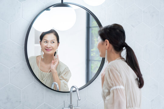 洗面所で身だしなみを整えるシニア女性