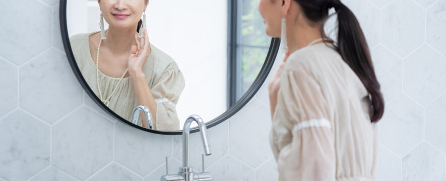 洗面所で身だしなみを整えるシニア女性