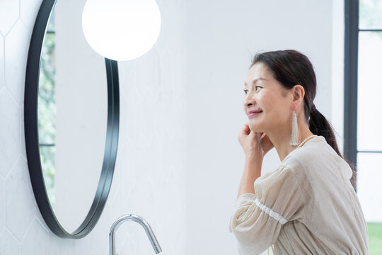 洗面所で身だしなみを整えるシニア女性