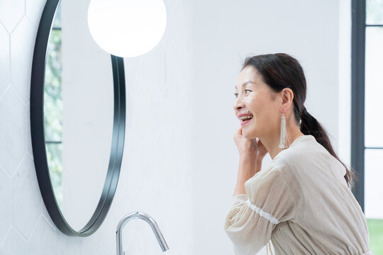 洗面所で身だしなみを整えるシニア女性