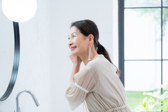 洗面所で身だしなみを整えるシニア女性