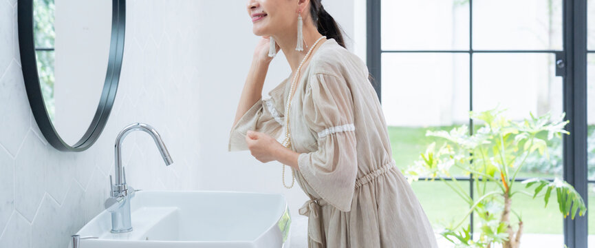 洗面所で身だしなみを整えるシニア女性
