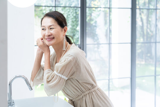 洗面所で身だしなみを整えるシニア女性