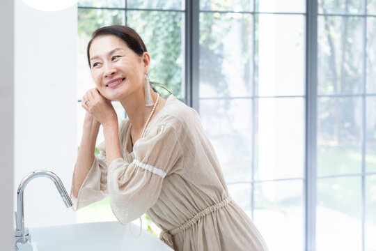 洗面所で身だしなみを整えるシニア女性