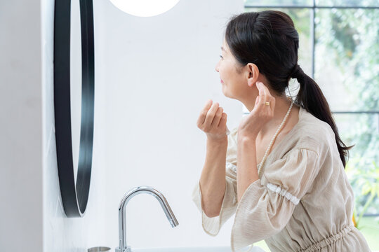 洗面所で身だしなみを整えるシニア女性 - Powered by Adobe