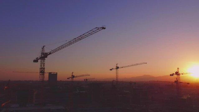 Jib cranes symbol of work and progress. Construction of buildings in Santiago de Chile. Sunset or sunrise in the city. drone video 4k