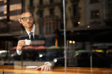 Handsome businessman enjoy in fresh coffee. Young man in suit drinking coffee in cafe.