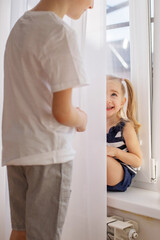 Children play hide and seek behind the curtain