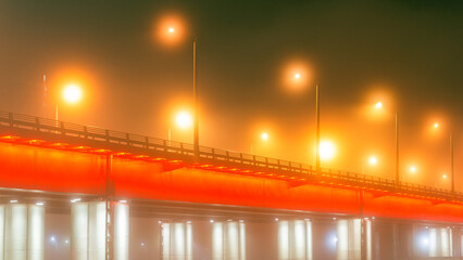 View of the bridge in the fog with beautiful illumination. Beautiful misty cityscape.