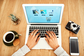 Fototapeta premium Always thinking outside the box for my blog. High angle shot of an unrecognizable businesswoman sitting indoors alone and using her laptop to blog.